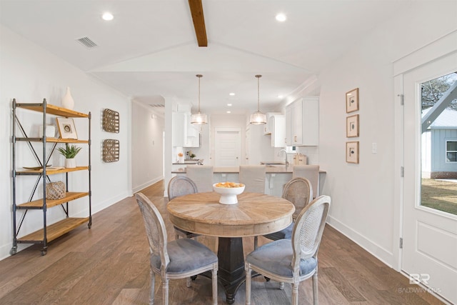 dining room with sink, vaulted ceiling with beams, and dark wood-type flooring