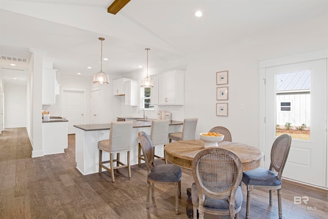 dining area with vaulted ceiling with beams, dark hardwood / wood-style floors, and sink