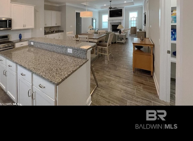 4844 E Cypress Loop, Orange Beach, AL 36561 - kitchen featuring stainless steel microwave, crown molding, a center island, a fireplace, and open floor plan
