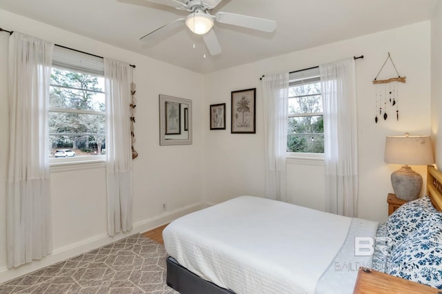 bedroom with a ceiling fan, light wood-type flooring, multiple windows, and baseboards