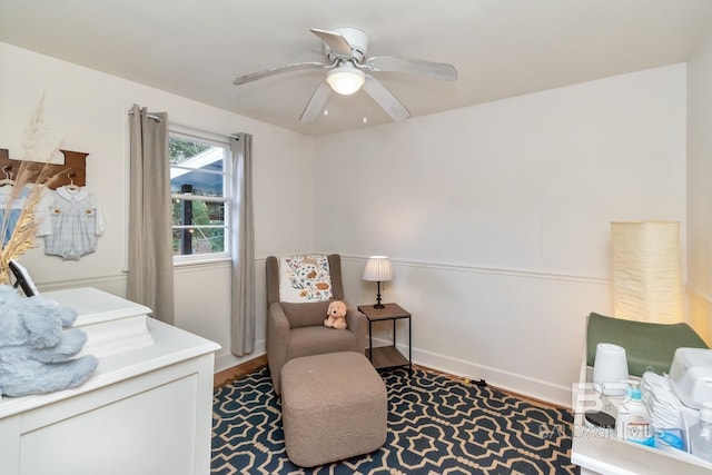 living area featuring baseboards, a ceiling fan, and wood finished floors