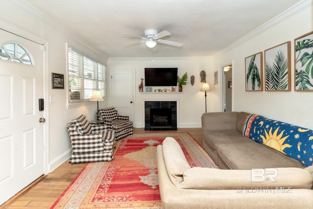 living room featuring baseboards, ceiling fan, ornamental molding, wood finished floors, and a fireplace