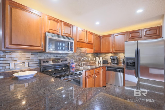 kitchen with dark stone countertops, sink, stainless steel appliances, and tasteful backsplash