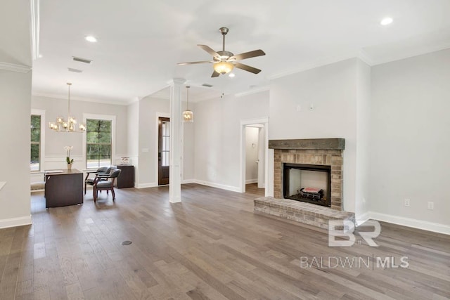 living room with ceiling fan with notable chandelier, hardwood / wood-style flooring, ornamental molding, a fireplace, and decorative columns