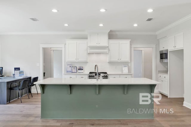 kitchen featuring a kitchen island with sink, white cabinets, and appliances with stainless steel finishes