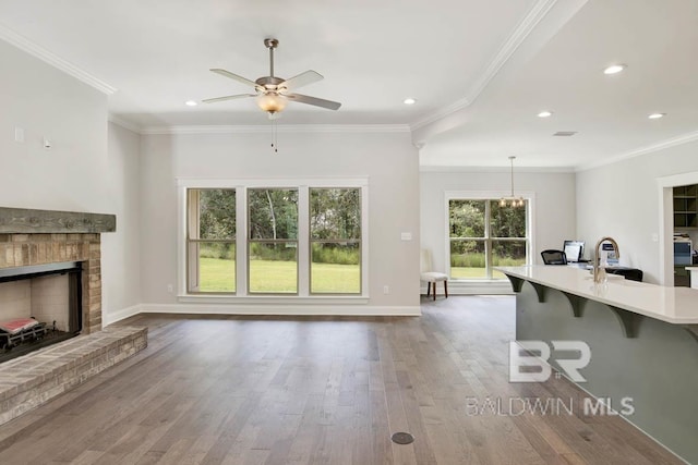 unfurnished living room featuring sink, crown molding, a brick fireplace, light hardwood / wood-style flooring, and ceiling fan