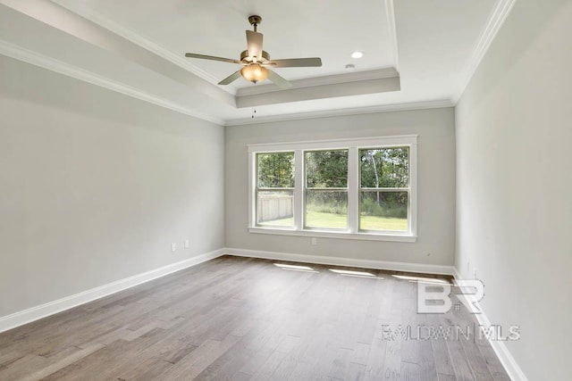 unfurnished room featuring wood-type flooring, a raised ceiling, ceiling fan, and ornamental molding