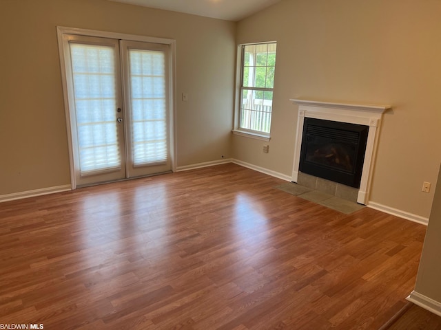 unfurnished living room with lofted ceiling, light hardwood / wood-style floors, and french doors