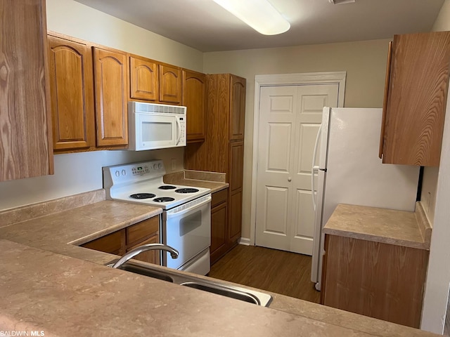 kitchen with white appliances, dark hardwood / wood-style floors, and sink
