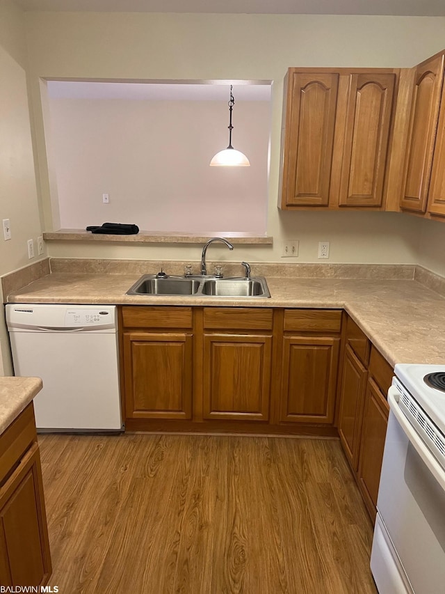 kitchen featuring light hardwood / wood-style flooring, pendant lighting, white appliances, and sink