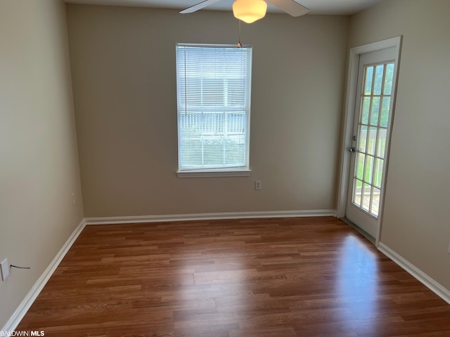 spare room with dark hardwood / wood-style flooring, ceiling fan, and a healthy amount of sunlight