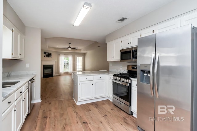 kitchen with kitchen peninsula, appliances with stainless steel finishes, white cabinets, and ceiling fan