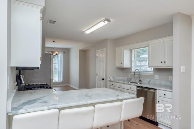 kitchen with visible vents, a peninsula, stainless steel appliances, white cabinetry, and a sink