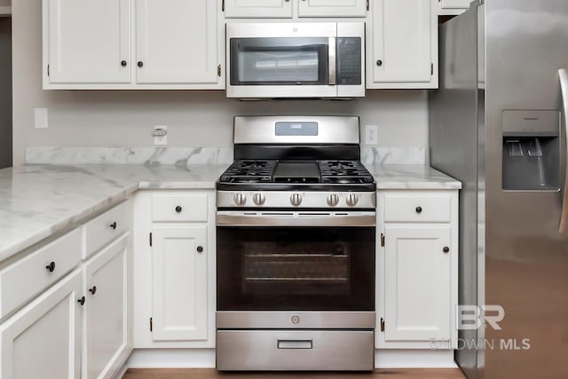 kitchen featuring white cabinets, light stone countertops, and appliances with stainless steel finishes