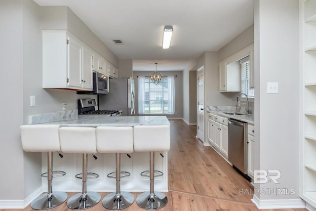 kitchen with kitchen peninsula, white cabinetry, sink, and stainless steel appliances