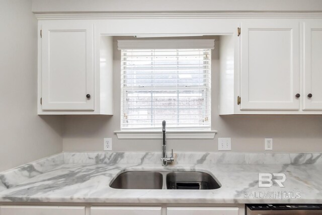 kitchen featuring white cabinetry, sink, dishwashing machine, and light stone counters