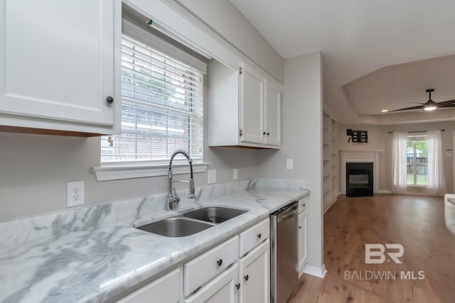 kitchen featuring dishwasher, white cabinetry, a sink, open floor plan, and a glass covered fireplace
