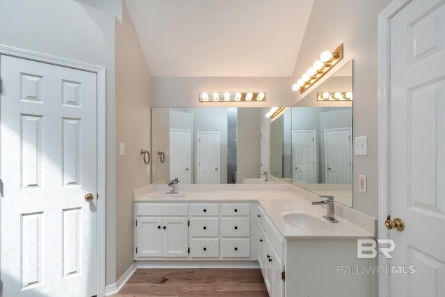 bathroom with hardwood / wood-style floors, vanity, and vaulted ceiling