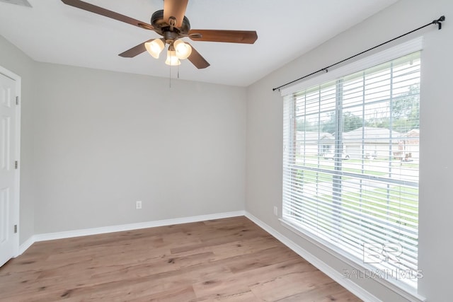 spare room featuring baseboards, light wood-type flooring, and a ceiling fan