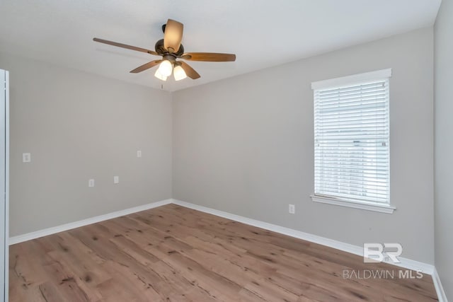 spare room featuring baseboards, wood finished floors, and a ceiling fan