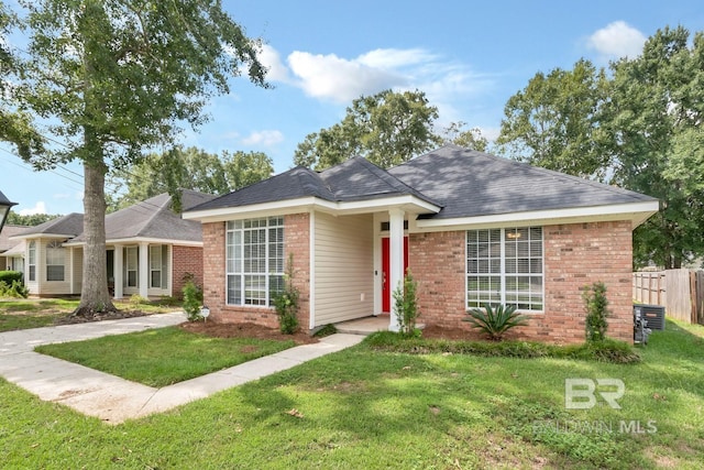 ranch-style home featuring a front lawn, fence, and brick siding