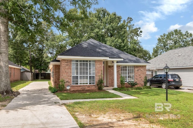 view of front of property featuring brick siding, concrete driveway, fence, and a front lawn