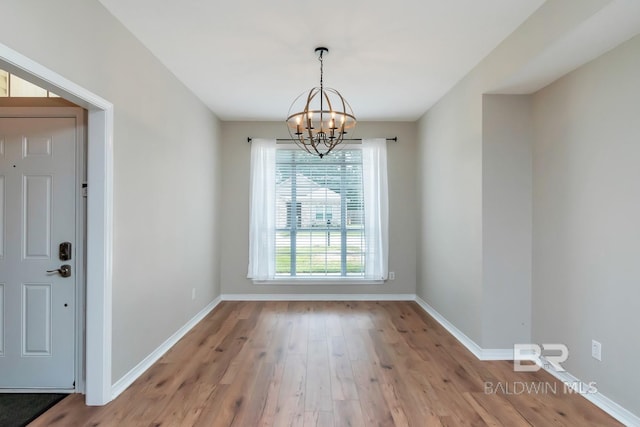 unfurnished dining area with light wood-style floors, baseboards, and a chandelier