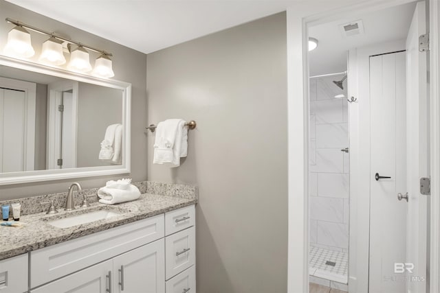 bathroom featuring a tile shower and vanity