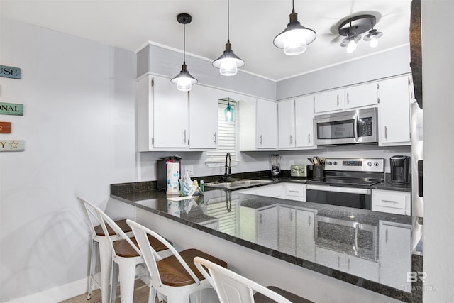 kitchen featuring appliances with stainless steel finishes, white cabinetry, dark stone counters, and kitchen peninsula