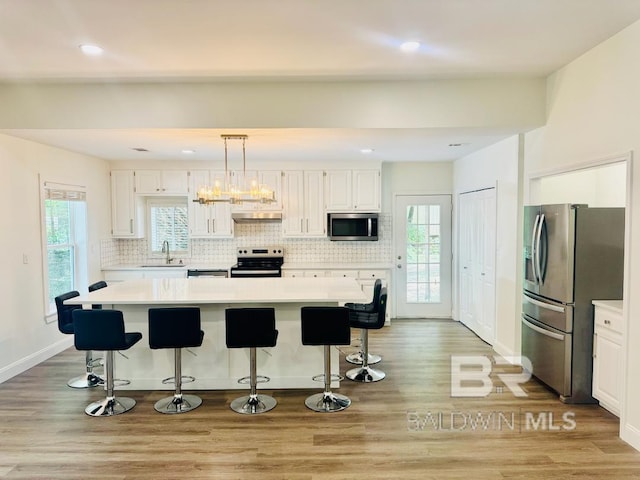 2663 Demetropolis Rd, Mobile, AL 36693 - kitchen featuring appliances with stainless steel finishes, light countertops, white cabinets, decorative backsplash, and light wood-style floors