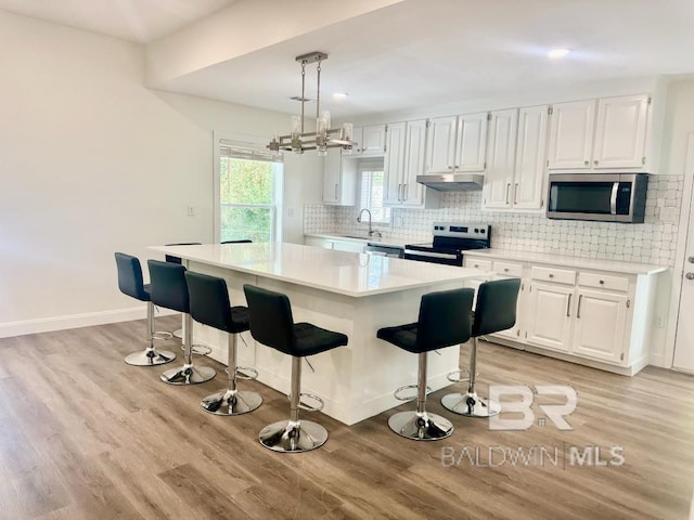 2663 Demetropolis Rd, Mobile, AL 36693 - kitchen featuring appliances with stainless steel finishes, under cabinet range hood, light wood-style floors, light countertops, and recessed lighting