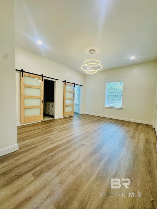 2663 Demetropolis Rd, Mobile, AL 36693 - unfurnished living room featuring a barn door, wood finished floors, and a chandelier