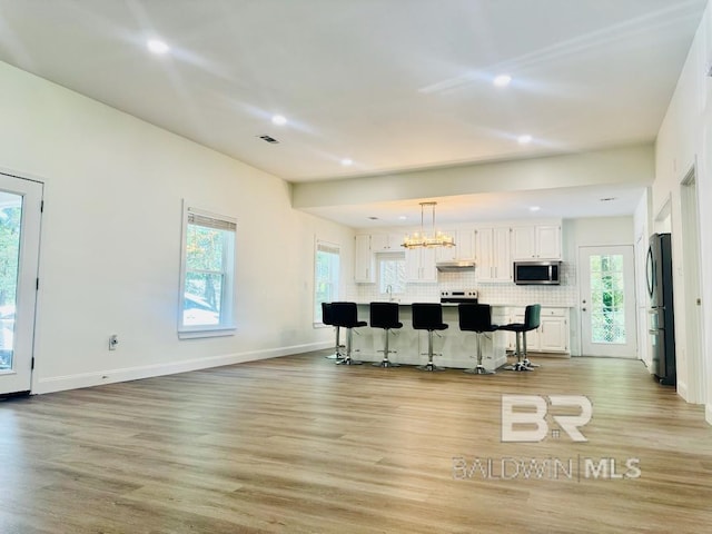 2663 Demetropolis Rd, Mobile, AL 36693 - kitchen with appliances with stainless steel finishes, white cabinetry, recessed lighting, a breakfast bar, and light wood finished floors