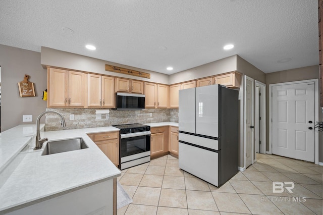 kitchen featuring freestanding refrigerator, electric range, stainless steel microwave, a sink, and light brown cabinets