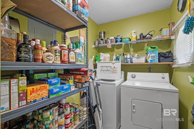 clothes washing area with washing machine and clothes dryer and a textured ceiling