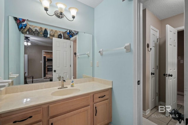 bathroom with tile patterned flooring, vanity, a textured ceiling, and baseboards