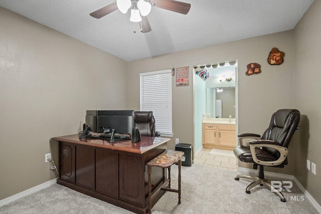 office area with light colored carpet, a ceiling fan, baseboards, and a textured ceiling