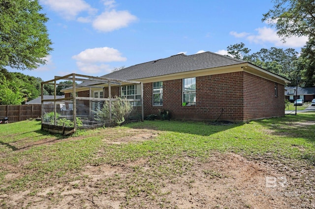 rear view of property with brick siding, a garden, and a shingled roof