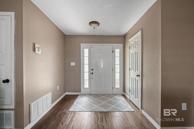 foyer with dark wood-style floors, baseboards, and a textured ceiling
