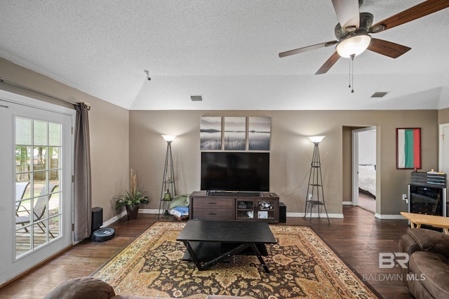 living area with lofted ceiling, wood finished floors, ceiling fan, baseboards, and a textured ceiling