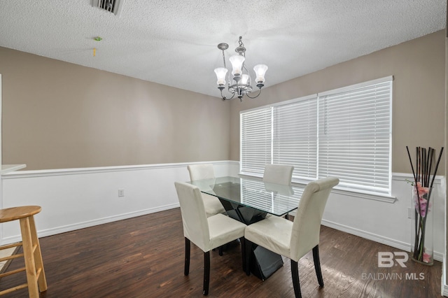 dining area featuring wood finished floors, a chandelier, and a textured ceiling
