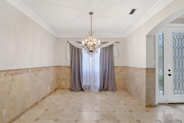 unfurnished dining area with crown molding, a chandelier, and tile walls