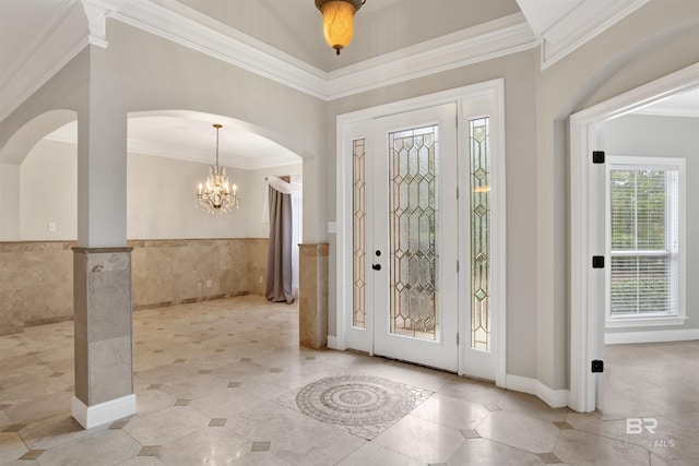 entrance foyer featuring tile walls, crown molding, and a chandelier