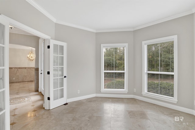 spare room with crown molding, french doors, and an inviting chandelier