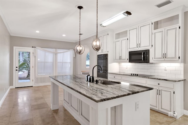 kitchen featuring a kitchen island with sink, black appliances, white cabinets, sink, and dark stone countertops