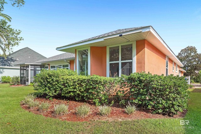 36 Lagoon Dr, Gulf Shores, AL 36542 - view of side of property with a yard, stucco siding, a sunroom, and a shingled roof