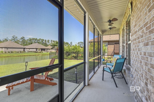 unfurnished sunroom with ceiling fan and a water view