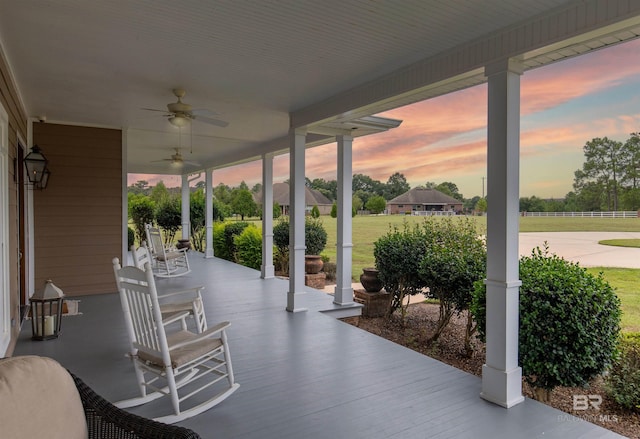 patio terrace at dusk featuring a lawn and ceiling fan