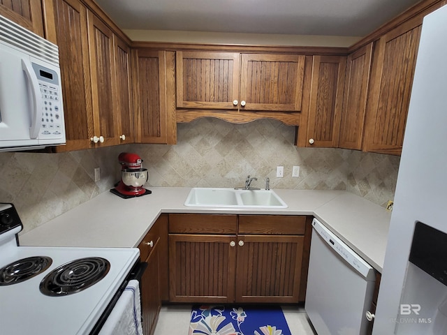2200 W 2nd St Unit B-106, Gulf Shores, AL 36542 - kitchen with white appliances, a sink, decorative backsplash, and brown cabinetry