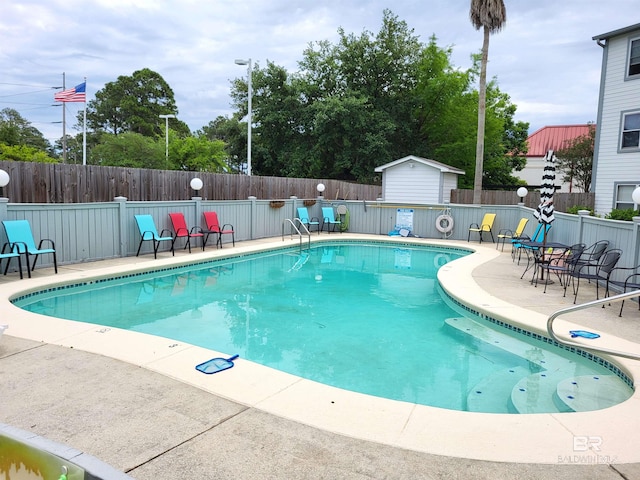 2200 W 2nd St Unit B-106, Gulf Shores, AL 36542 - community pool with a fenced backyard, a patio area, a storage unit, and an outdoor structure